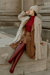 a lady in a red sweater, a brown plaid skirt and a beige coat